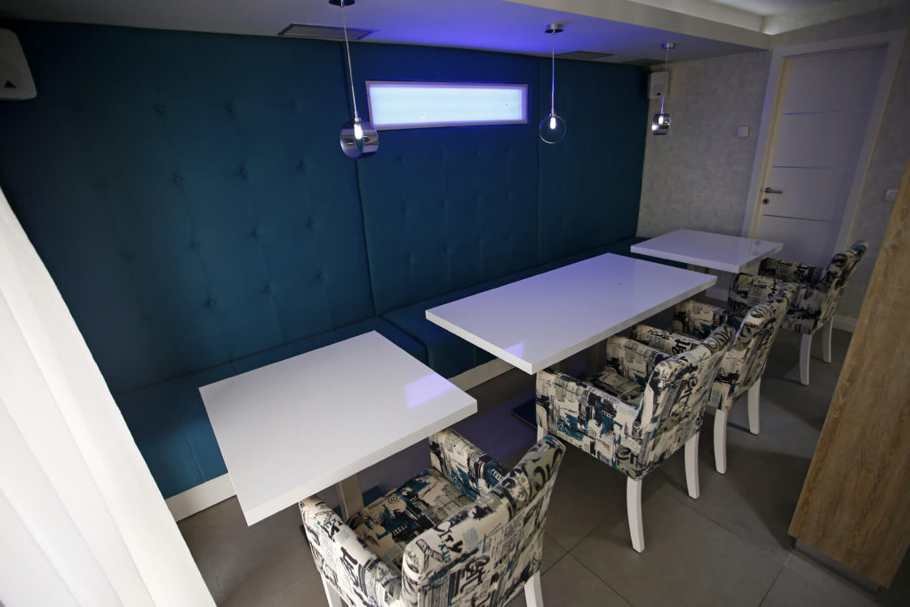 Lounge bar prostorija s plavim tapeciranim zidom i tapaciranim stolicama
